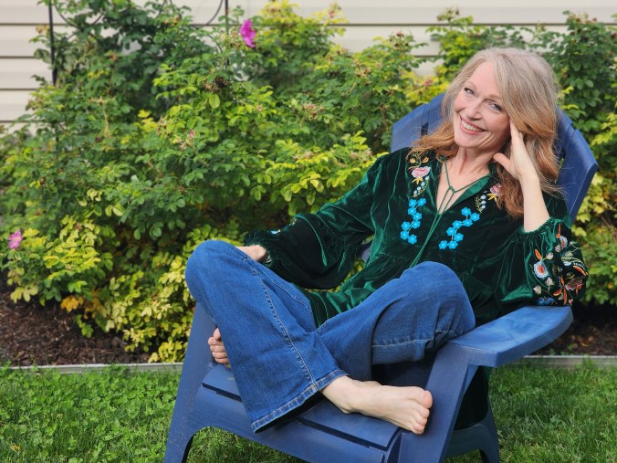 Carla in an Adirondack chair in a flower garden.